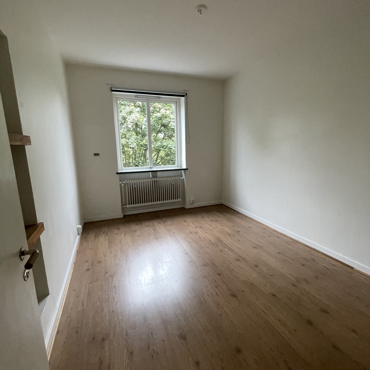 Vit hall med trägolv med passager till kök och vardagsrum  i Halmstad