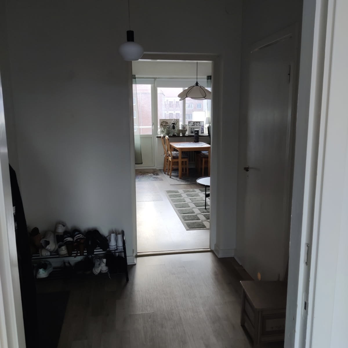 Vit hall med trägolv med passager till kök och vardagsrum  i Halmstad